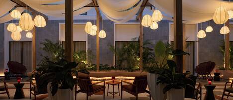 Un moderno espacio lounge interior con lámparas colgantes, asientos cómodos y plantas en macetas.