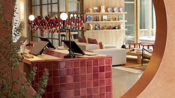 A modern interior with a circular mirror reflecting a living area, a wooden desk with a laptop, and a bookshelf.