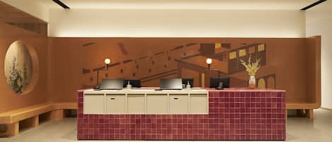A reception desk with a tiled counter, a vase with flowers, and a wall with abstract patterns.