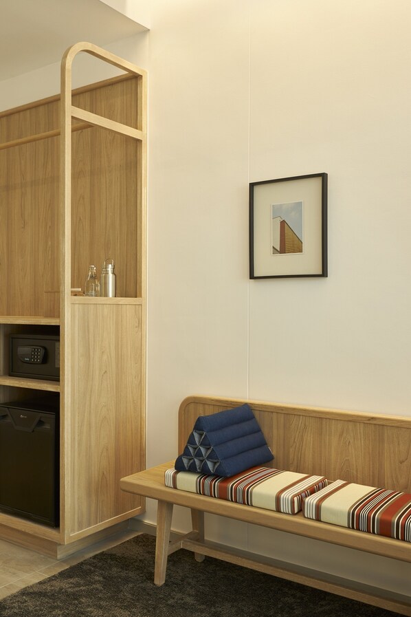 A modern room with a wooden cabinet, a bench with striped cushions, and a framed picture on the wall.