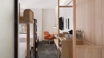 A compact hotel room with a bunk bed, a desk with a chair, a television, and a small seating area.