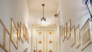 A staircase with a handrail, leading to a door with decorative panels and a ceiling light. - Casa Al Duomo-Apartment in the historic center of Merano (Merano)