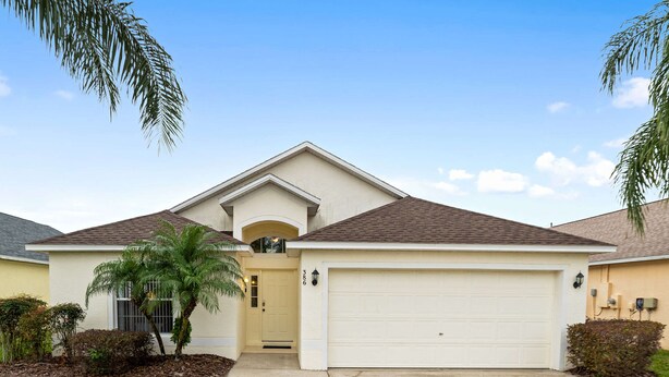 A single-story house with a garage, a small front porch, and a palm tree. - Malaki (Davenport)