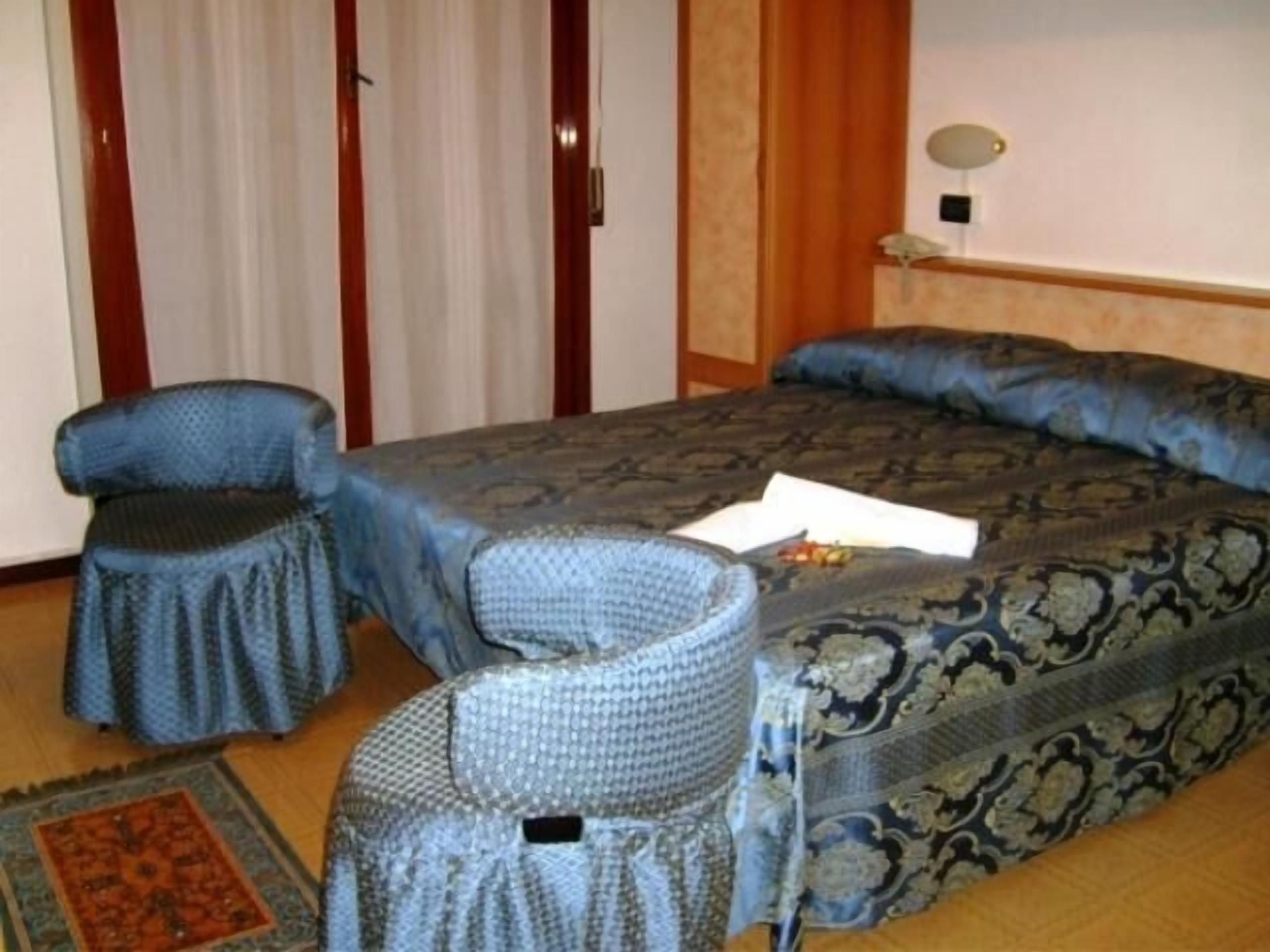 Una habitación de hotel con una cama, una silla, una mesita y una alfombra.