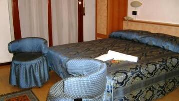 Una habitación de hotel con una cama, una silla, una mesita y una alfombra.