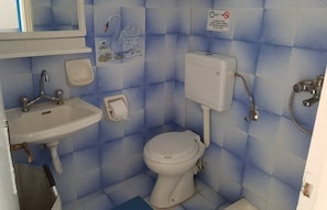 A bathroom with a sink, toilet, and shower. There is a sign prohibiting the disposal of non-biodegradable items. - MM Studios Perissa (Santorini)