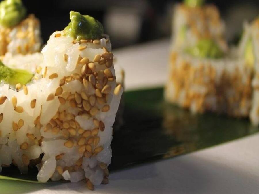 Sushi rolls with sesame seeds and wasabi on a plate.
