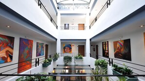 Un vestíbulo moderno con obras de arte en las paredes, una escalera de cristal y plantas en macetas.