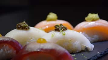 A variety of sushi dishes on a dark slate plate.