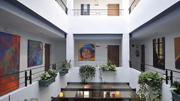A modern hotel lobby with a central staircase, artwork on the walls, and potted plants.