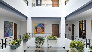 Un atrio de varios niveles con barandillas de vidrio, plantas en macetas y obras de arte en las paredes.