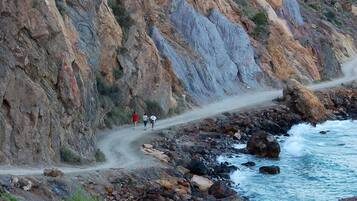 Una carretera costera rocosa con un sendero estrecho y un litoral pedregoso.