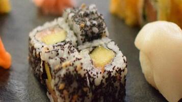 Un piatto di sushi assortito, con diversi tipi di sushi, tra cui nigiri e involtini, su un piatto in ardesia scura.