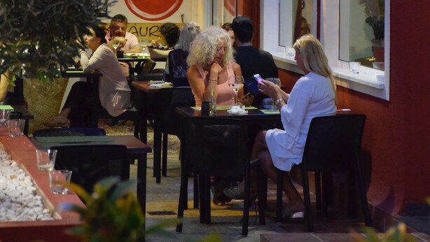 Un área de comedor al aire libre con mesas y sillas, palmeras y un letrero que dice "MANDUKA".