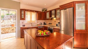 Una cocina moderna con armarios de madera, electrodomésticos de acero inoxidable y una isla grande con un bol de frutas.