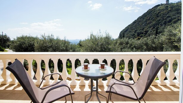 Un balcón con una mesa redonda y dos sillas, con vista a un paisaje montañoso.