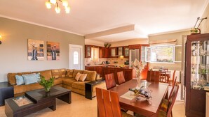 Una sala de estar moderna con un sofá modular, una mesa de comedor y una cocina al fondo.