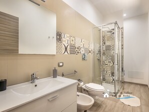 Et moderne badeværelse med en stor vask, toilet og bruseområde.