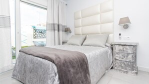 A bedroom with a large bed, a nightstand, a lamp, and a view of the outside. - Cubo's Cozy & Modern Sol de Malaga / Private pool / Free Wifi (Málaga)