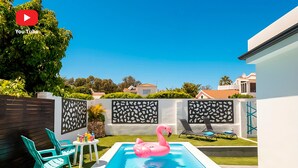 A backyard with a swimming pool, a pink flamingo float, and a white fence with decorative panels. - Cubo's Cozy & Modern Sol de Malaga / Private pool / Free Wifi (Málaga)