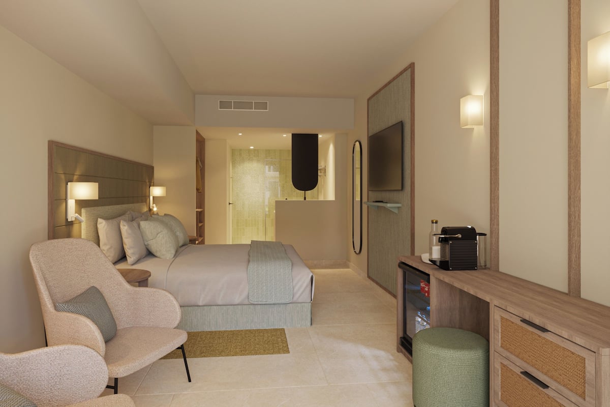 Quarto de hotel com uma cama, uma cadeira, uma escrivaninha, uma televisão e um espelho.