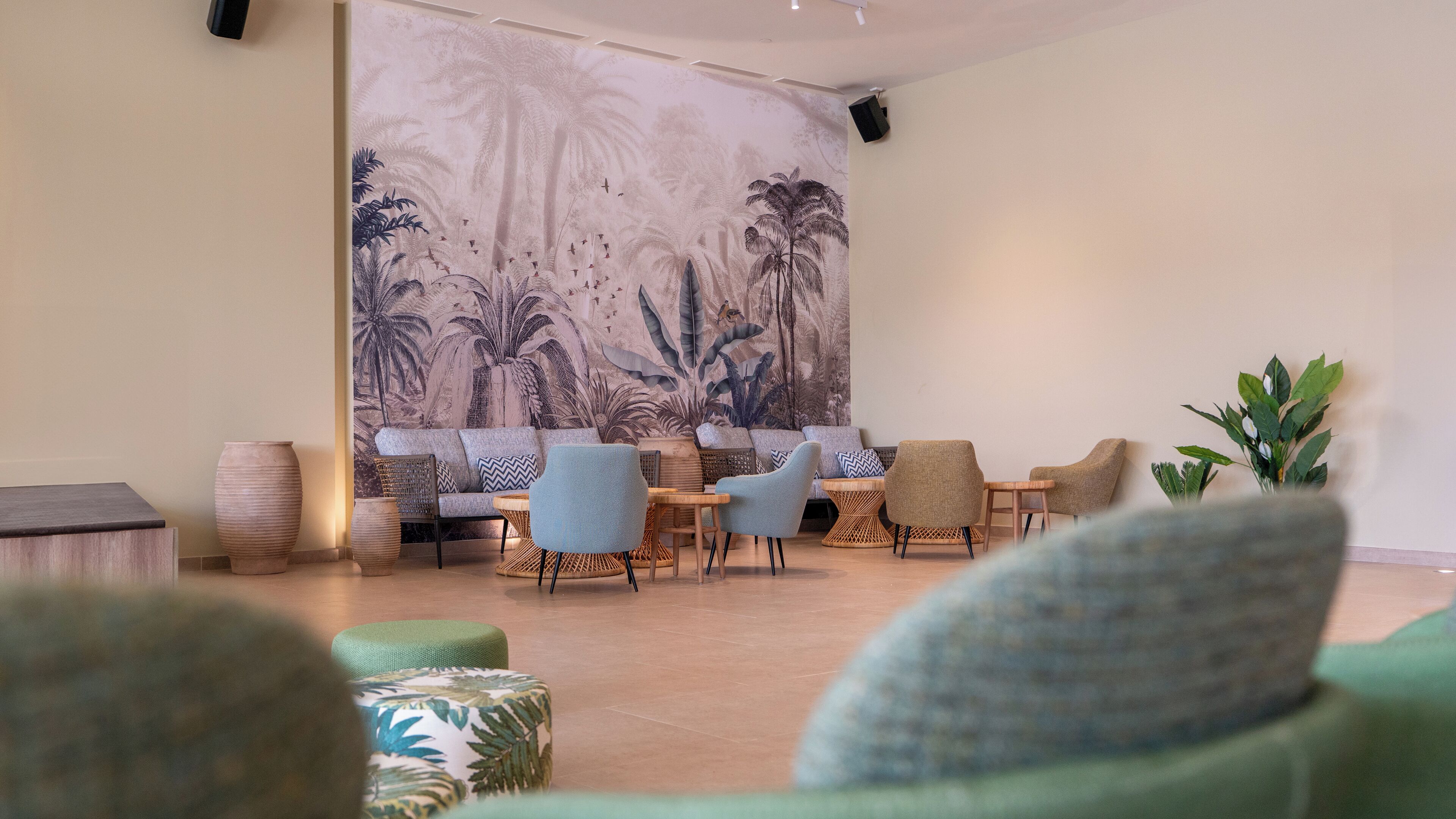 A modern lounge area with a large tropical-themed mural, comfortable seating, and a minimalist design.
