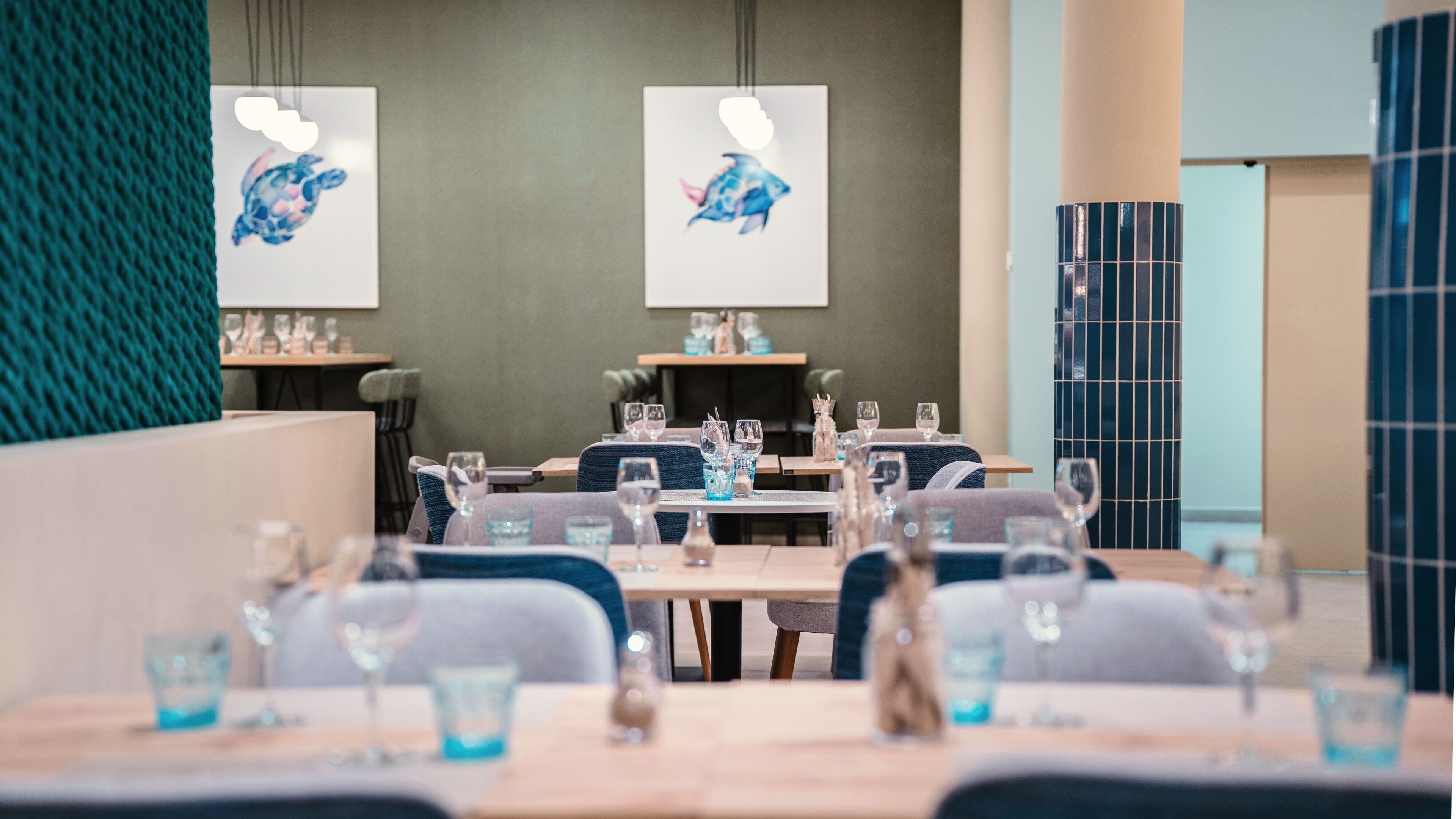 A modern dining area with tables set for dining, chairs, and decorative wall art.