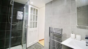 Ein modernes Badezimmer mit Duschkabine aus Glas, einem weißen Waschbecken und einem Spiegel.