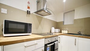 Eine Küche mit Mikrowelle, Backofen und einer Edelstahl-Dunstabzugshaube.