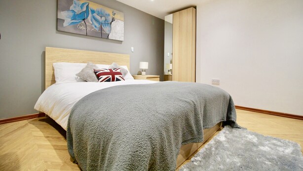 Ein Schlafzimmer mit einem Bett, einem Bild an der Wand, einem Nachttisch und einem Spiegel.