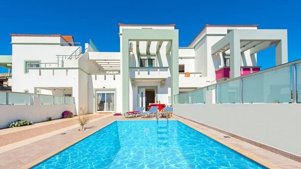 A modern pool area with clear blue water, surrounded by contemporary white buildings with balconies. - Charming Seaside Villa in South Rhodes (Blue Pearl)  (Gennadi)