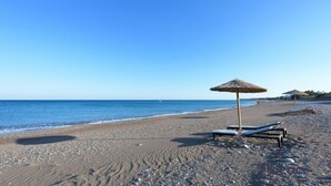 A beach with a thatched umbrella and lounge chairs. - Charming Seaside Villa in South Rhodes (Blue Pearl)  (Gennadi)
