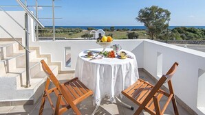 A balcony with a round table set for two, overlooking a scenic view of the sea and greenery. - Charming Seaside Villa in South Rhodes (Blue Pearl)  (Gennadi)