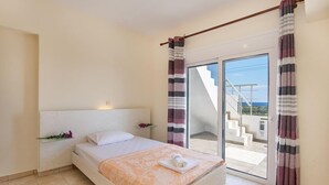 A bedroom with a bed, a nightstand, a window with curtains, and a view of a staircase leading to an outdoor area. - Charming Seaside Villa in South Rhodes (Blue Pearl)  (Gennadi)