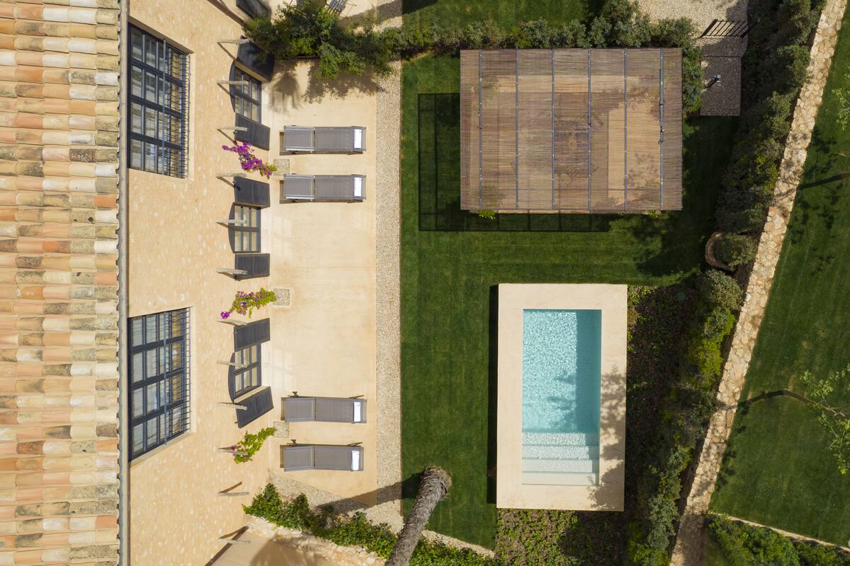 An aerial view of a property with a swimming pool, outdoor seating area, and a covered patio.