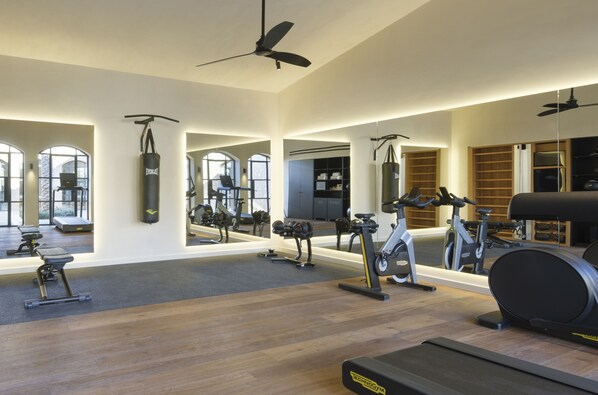 Un gimnasio amplio con diversos equipos de ejercicio, ventanas grandes y un diseño moderno.