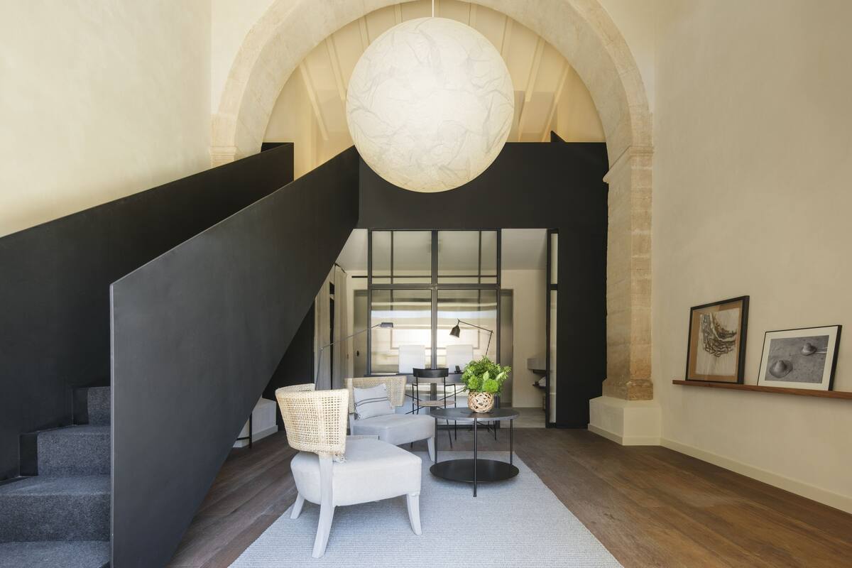 A modern interior with a staircase, a seating area, and a large arched ceiling.