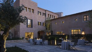 A building with a courtyard, outdoor seating, and a stone facade. - Can Ferrereta (Santanyi)