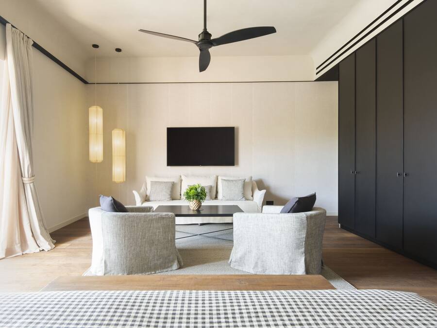 Una sala de estar moderna con un sofá, dos sillones, una mesa de centro y un ventilador de techo.