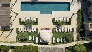 An aerial view of a hotel with a large rectangular swimming pool, multiple sun loungers, and a central circular feature. - Can Ferrereta (Santanyi)