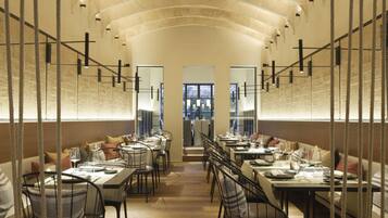 A restaurant with a long, curved ceiling and rows of tables and chairs.