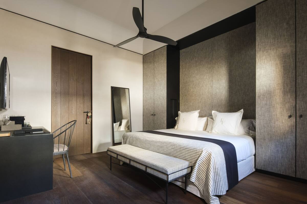 A modern bedroom with a large bed, a desk, and a chair.