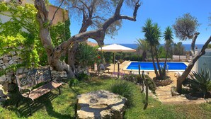 A pool area with a stone wall, a bench, and a view of the sea. - Villa Paiare with private pool on the Ionian sea (Torre Vado)