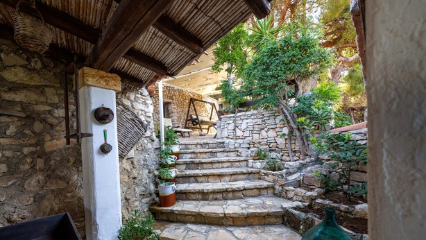 A stone staircase leading to a wooden bench under a thatched roof, surrounded by greenery and stone walls. - Villa Paiare with private pool on the Ionian sea (Torre Vado)