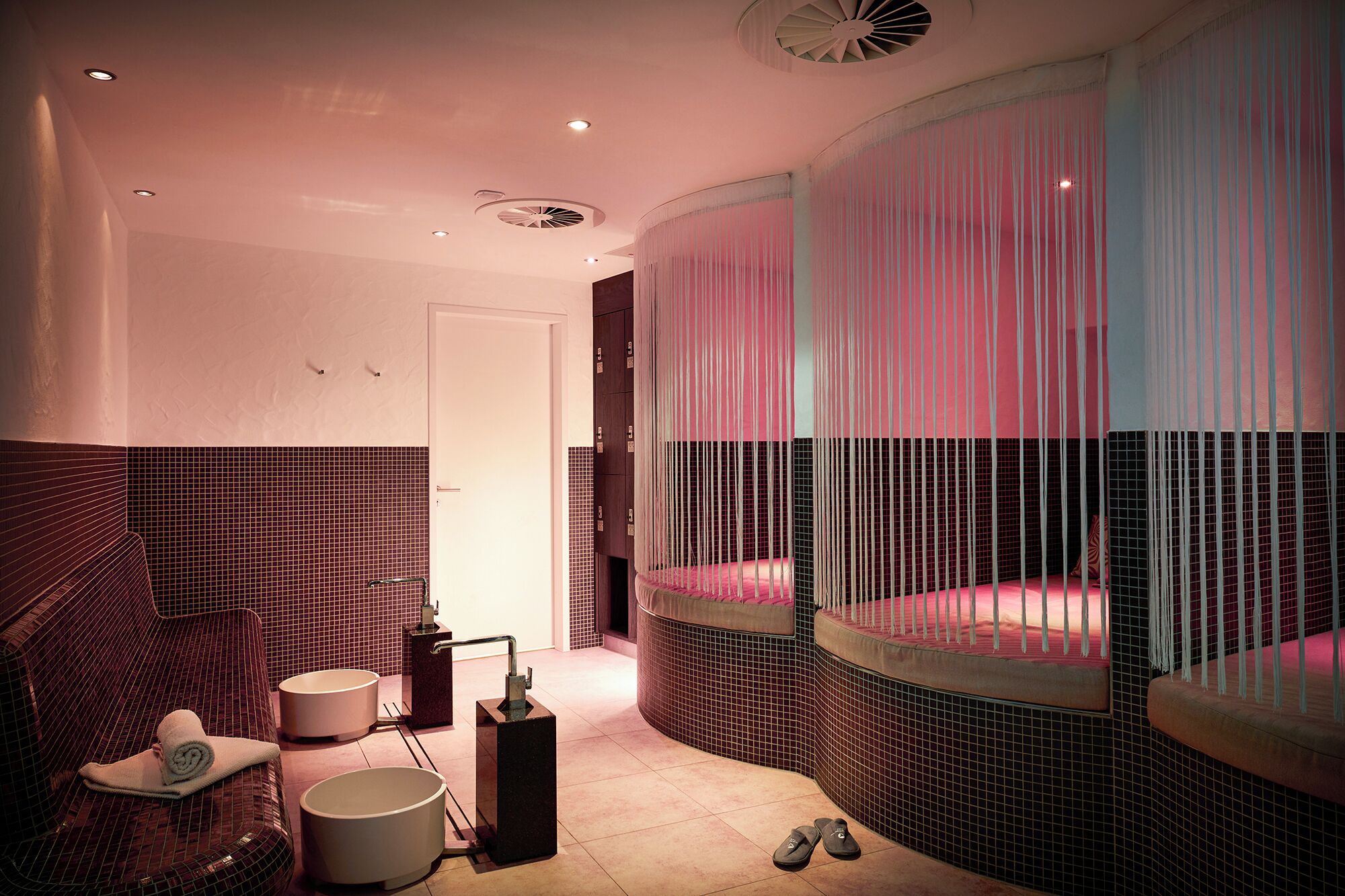 Une salle de bain moderne avec un banc incurvé, une grande baignoire et un espace douche doté de rideaux.