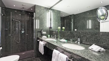 A modern bathroom with a glass-enclosed shower, two sinks, and a large mirror.