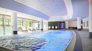 Ein Hallenbad mit Liegestühlen und einem modernen Deckenstil.