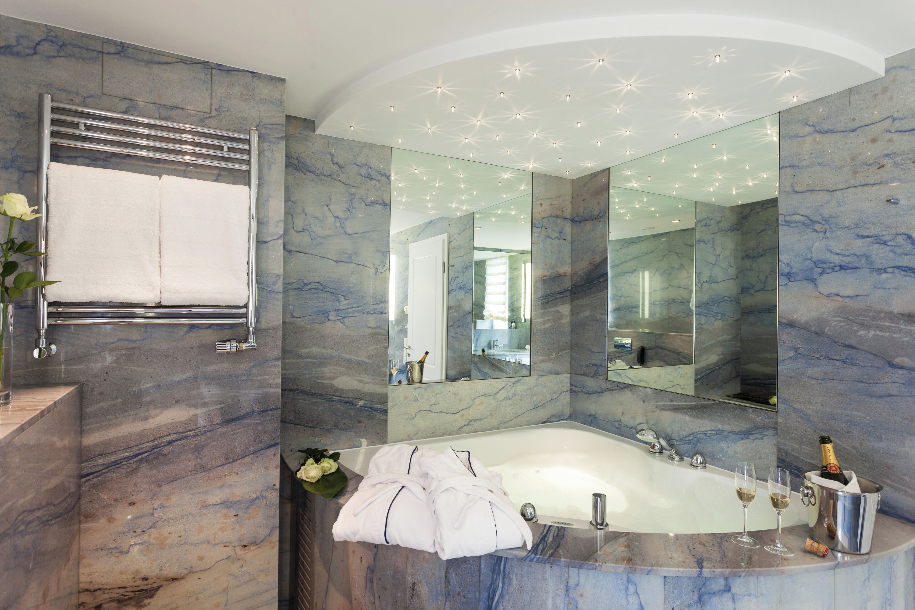 Un baño moderno con lavamanos de mármol, un espejo grande y una bañera.