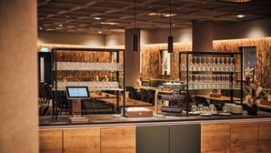 Ein Restaurantinneres mit holzverkleideten Wänden, einer Theke mit digitaler Menüanzeige und Regalen voller Gläser.
