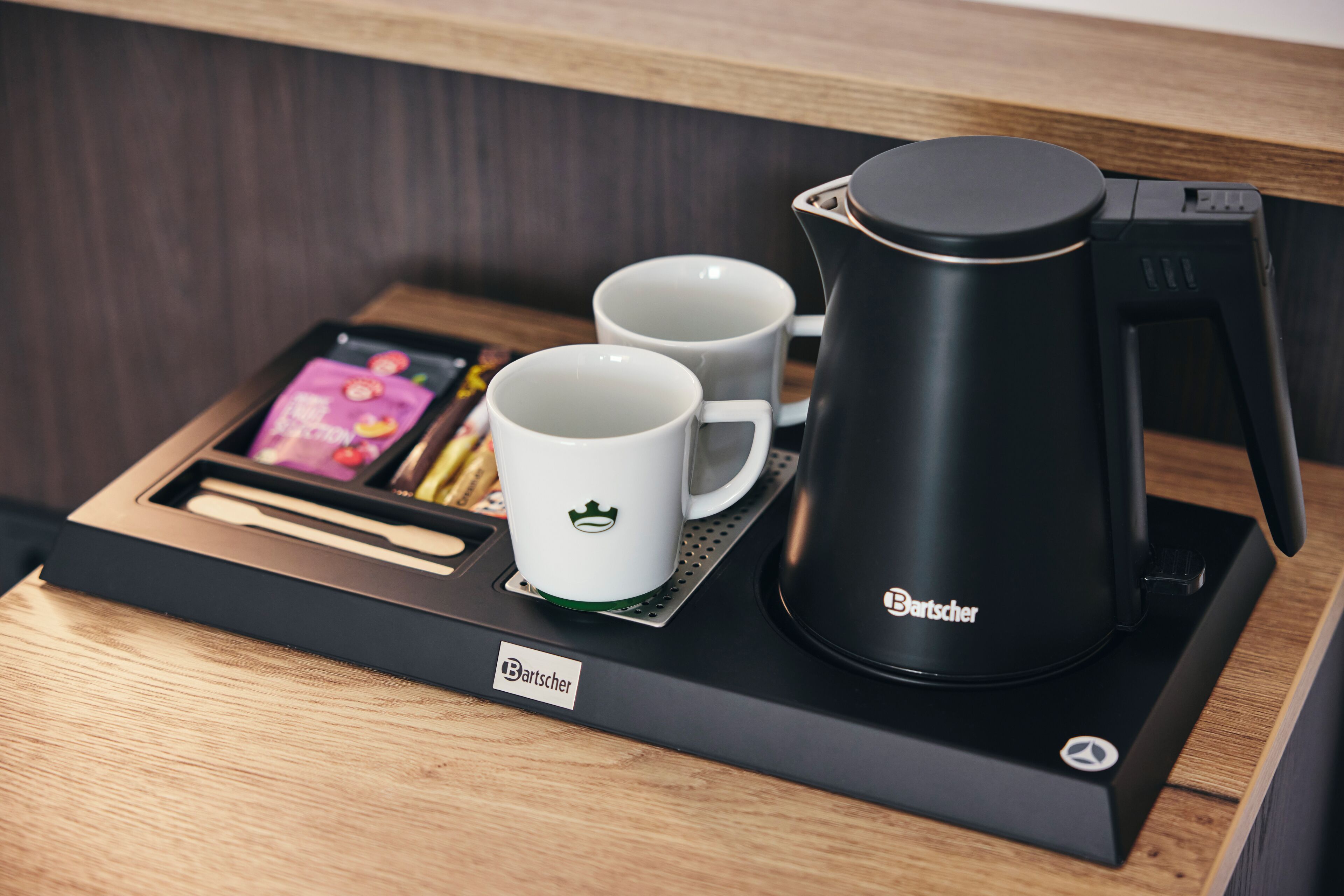 Eine Kaffeemaschine mit zwei weißen Tassen auf einem Holztablett.